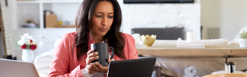 Woman working on computer holding a mug