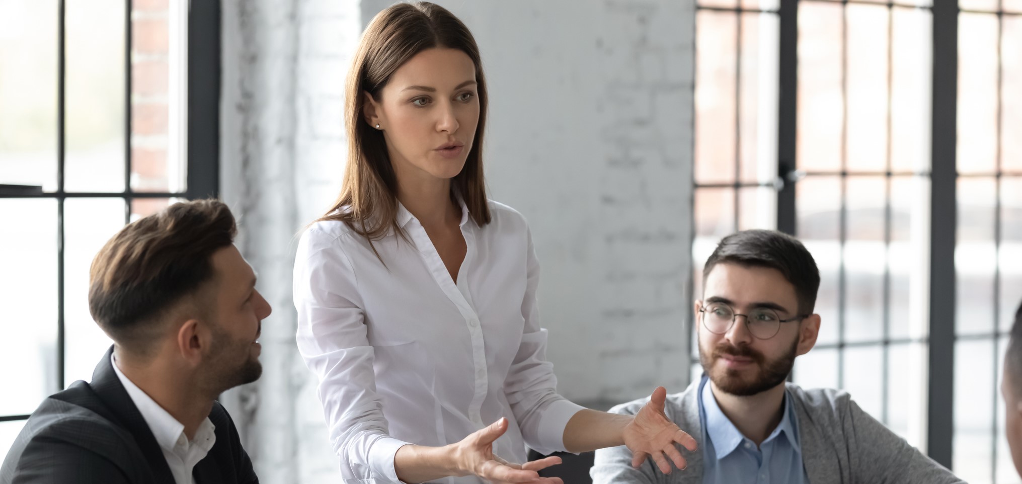 Image of a business woman speaking to two business men in a meeting 